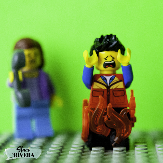 Lego scene - lego person crying with pants on fire, another lego person on the left side holding a phone, concerned
