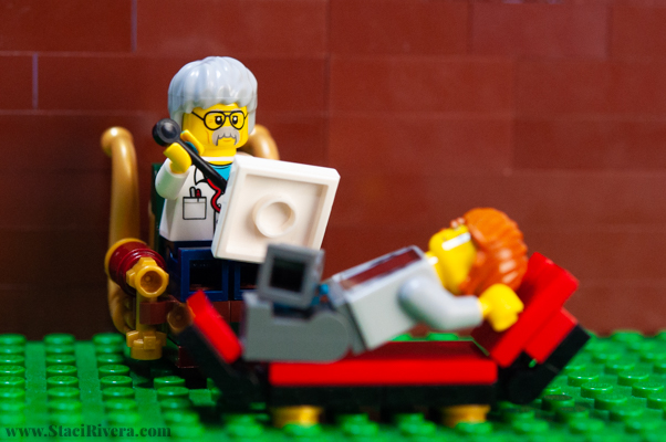 Lego scene - lego person laying on a counsellor couch, with lego person counsellor sitting writing